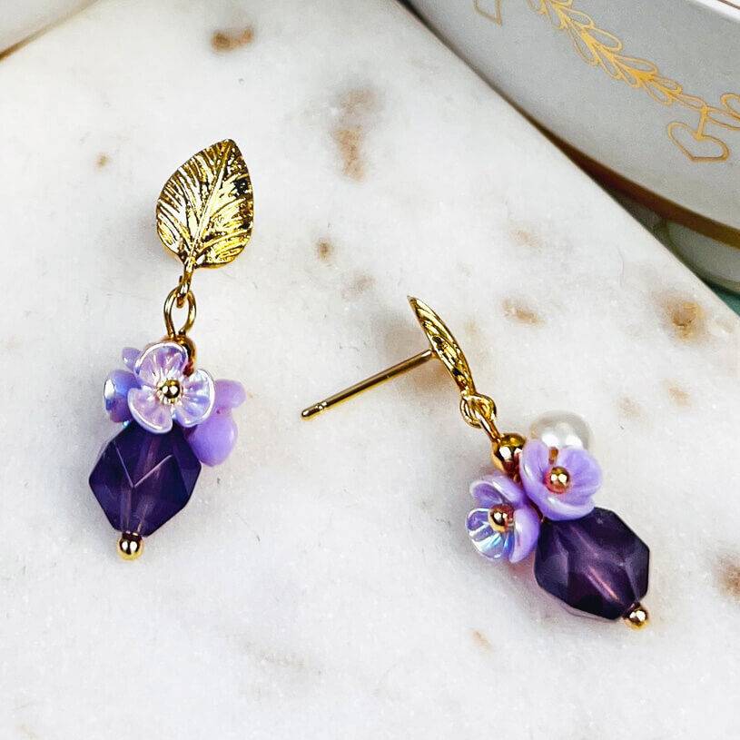 SchwesterSchwester Kleine vergoldete Ohrstecker in Blattform mit Blüten und Perle in Violett Im Verkauf